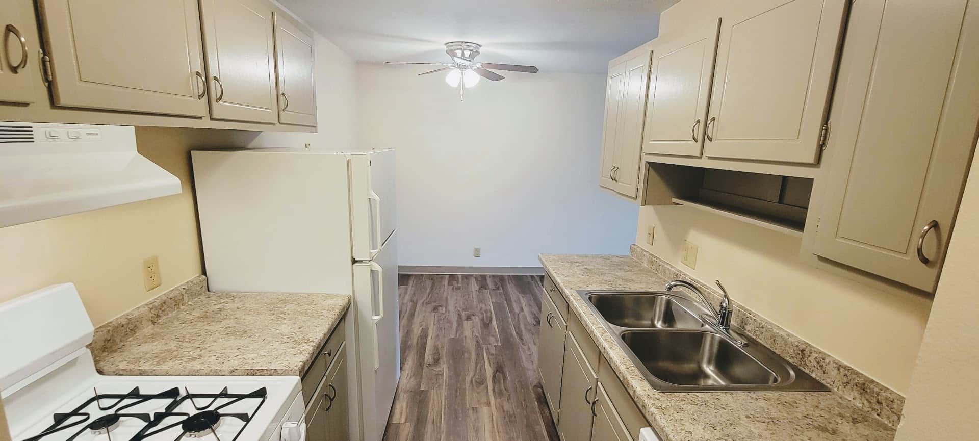 Apartment kitchen with new flooring and cabinets, dining room with a ceiling fan